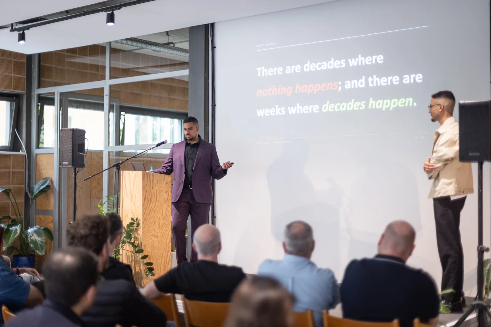 Two speakers on stage under the decades quote